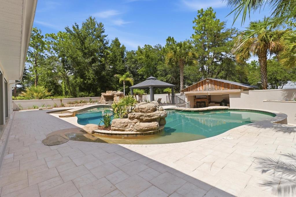 A backyard features a swimming pool with a rock island, a gazebo, and a patio — 91 S SCHOOL AVENUE, LECANTO, FL
