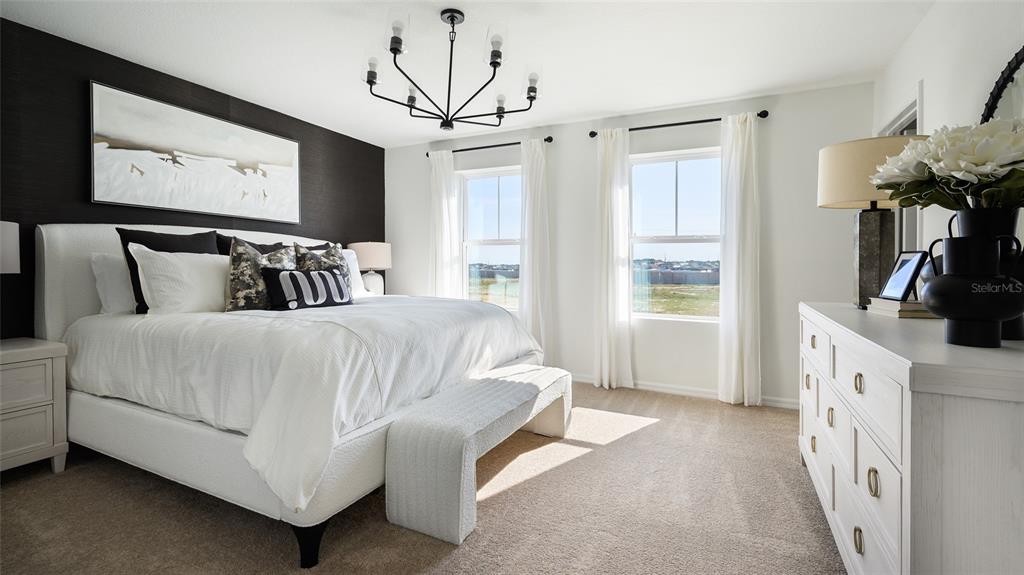 A bedroom features a white bed against a black accent wall, chandelier, and white dresser — 4523 WYNNSTONE DRIVE, DAVENPORT, FL