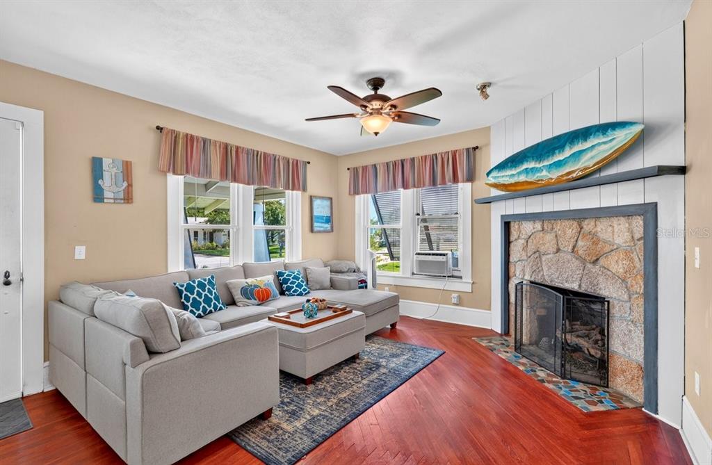 A living room features a stone fireplace, gray sectional sofa, and hardwood floors — 330 HARTFORD AVENUE, DAYTONA BEACH, FL