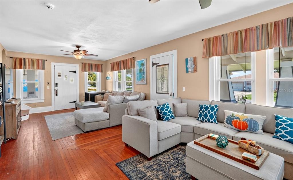 A living room features hardwood floors, two sectionals, and multiple windows with striped valances — 330 HARTFORD AVENUE, DAYTONA BEACH, FL