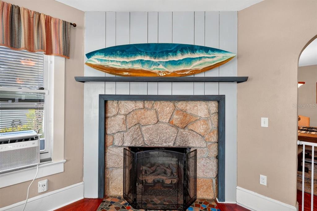 A stone fireplace with a surfboard art piece sits below a light blue shiplap wall — 330 HARTFORD AVENUE, DAYTONA BEACH, FL
