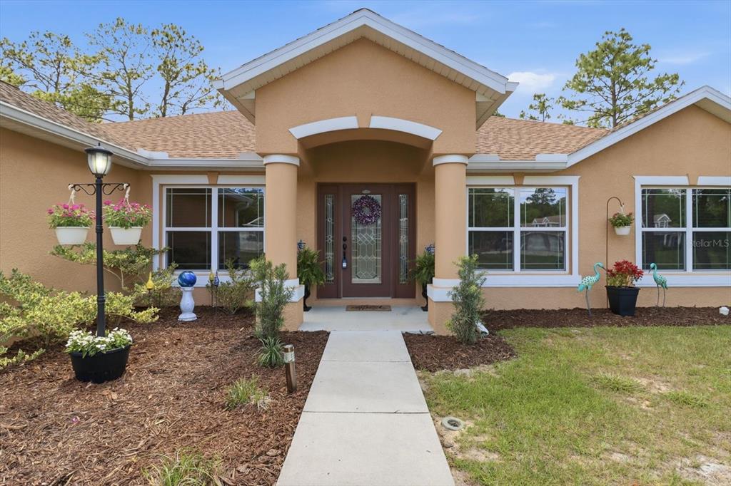 A tan house exterior features a covered entryway with columns and a front door — 5958 N ORCHIS TERRACE, BEVERLY HILLS, FL