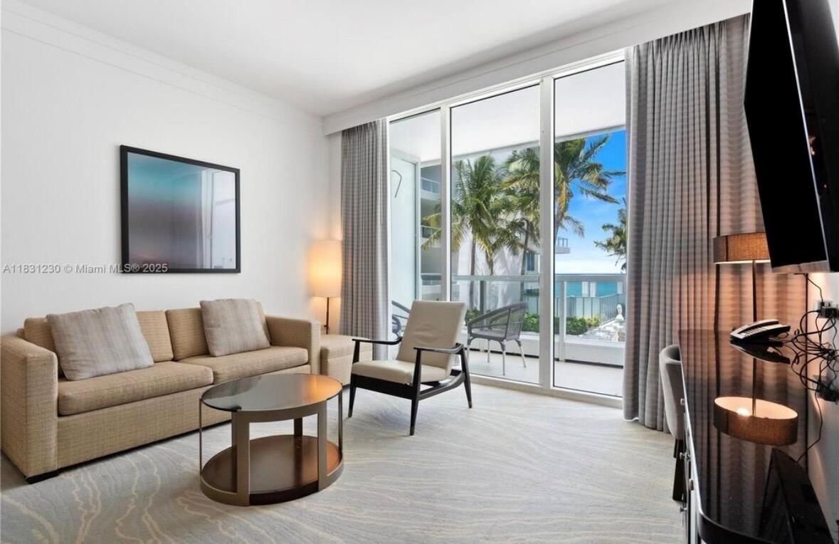 A living room features a beige sofa, a round coffee table, and a balcony view — 4391 Collins Avenue Unit 623, Miami Beach FL 33140, MIAMI BEACH, FL