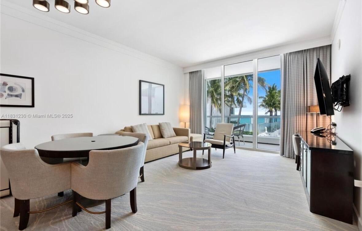 A living and dining area features a beige sofa, round table, and floor-to-ceiling balcony windows — 4391 Collins Avenue Unit 623, Miami Beach FL 33140, MIAMI BEACH, FL