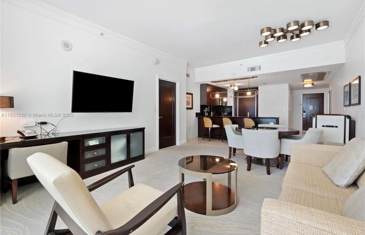 A living room features a television, a sofa, armchairs, and an open kitchen area — 4391 Collins Avenue Unit 623, Miami Beach FL 33140, MIAMI BEACH, FL