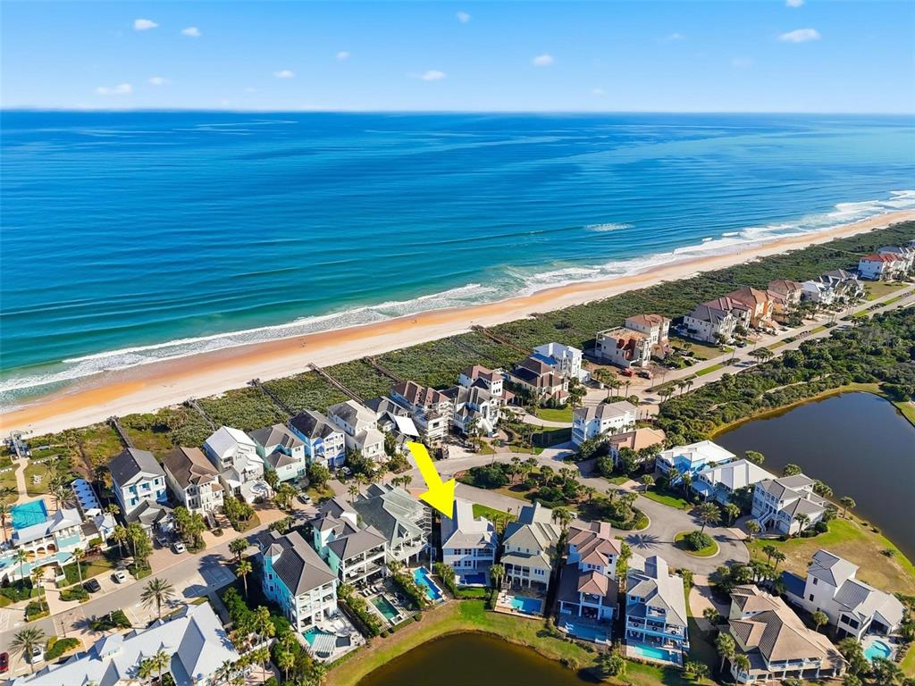 An aerial view shows a coastal neighborhood with houses, a beach, and a small lake — 527 CINNAMON BEACH LANE, PALM COAST, FL