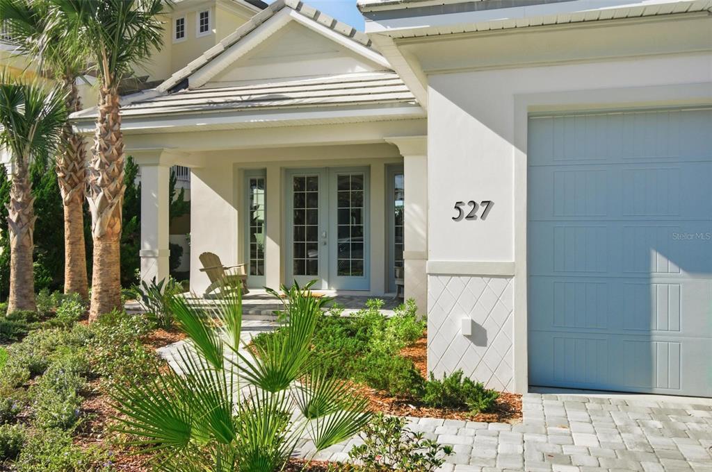 A white house exterior features a covered porch, light blue double doors, and a garage — 527 CINNAMON BEACH LANE, PALM COAST, FL