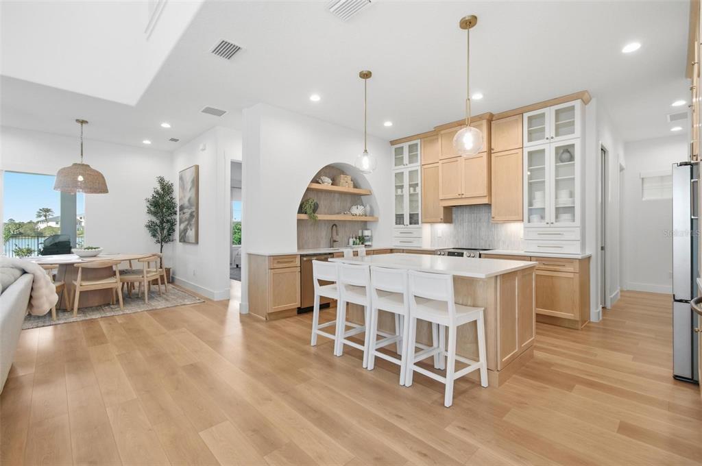 A modern kitchen features light wood cabinets, a white island with seating, and an arched alcove — 527 CINNAMON BEACH LANE, PALM COAST, FL