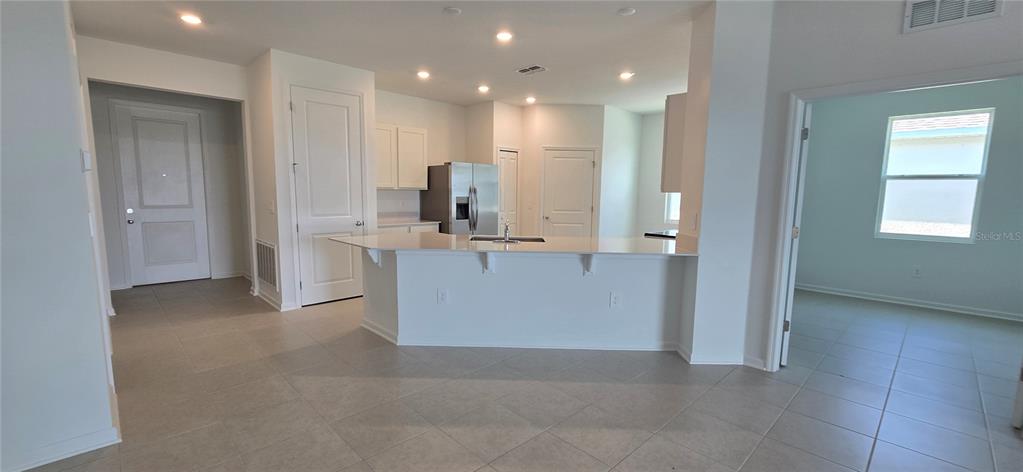 A kitchen with a breakfast bar, stainless steel refrigerator, and white cabinets on tile flooring — 2451 BLUESTONE ROAD, LAKE HAMILTON, FL