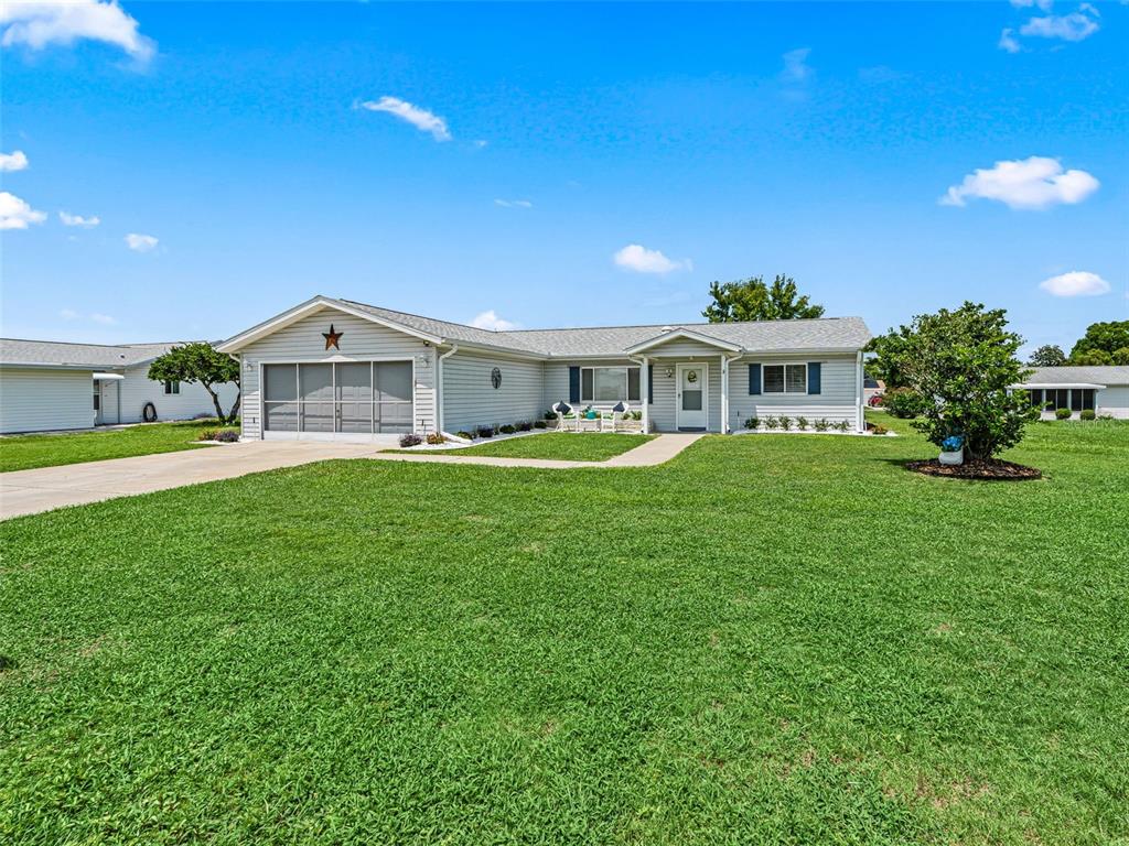A light-colored, single-story ranch house with a garage and a large front lawn — 17587 SE 106TH AVENUE, SUMMERFIELD, FL