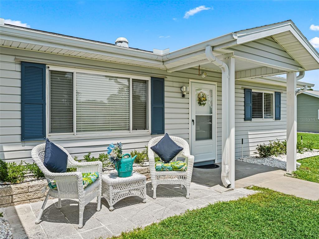 A light gray house exterior features a front porch with two white wicker chairs — 17587 SE 106TH AVENUE, SUMMERFIELD, FL