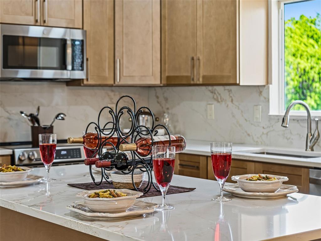 A kitchen island features three wine glasses, pasta bowls, and a wine rack — 17587 SE 106TH AVENUE, SUMMERFIELD, FL