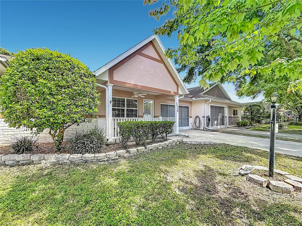 A single-story house with a front porch, tan siding, and a stone-lined garden bed — 9635 SW 94TH TERRACE UNIT B, OCALA, FL