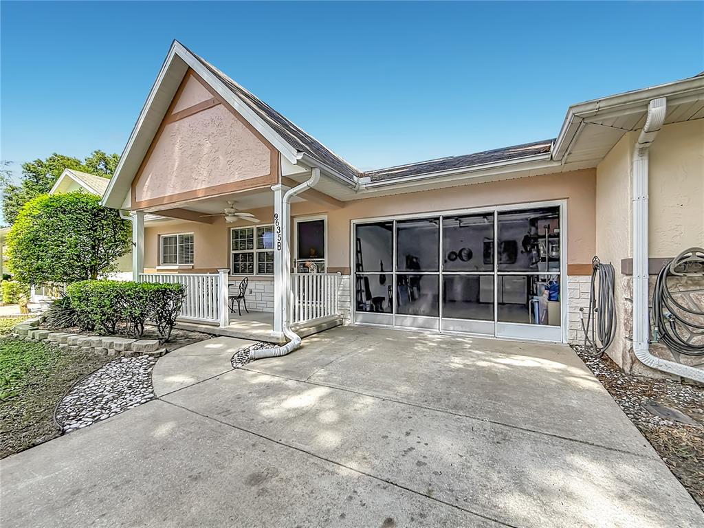 A house exterior features a covered porch, a concrete driveway, and a screened-in garage area — 9635 SW 94TH TERRACE UNIT B, OCALA, FL