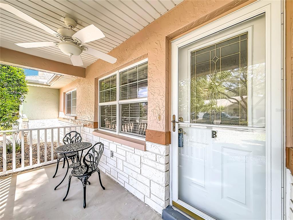 A covered porch features a ceiling fan, a small bistro set, and a white door — 9635 SW 94TH TERRACE UNIT B, OCALA, FL