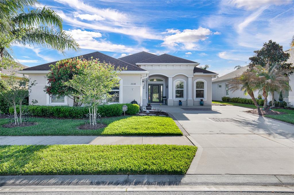 A single-story house with a beige stucco exterior, a concrete driveway, and a manicured lawn — 3338 BELLINO BOULEVARD, NEW SMYRNA BEACH, FL