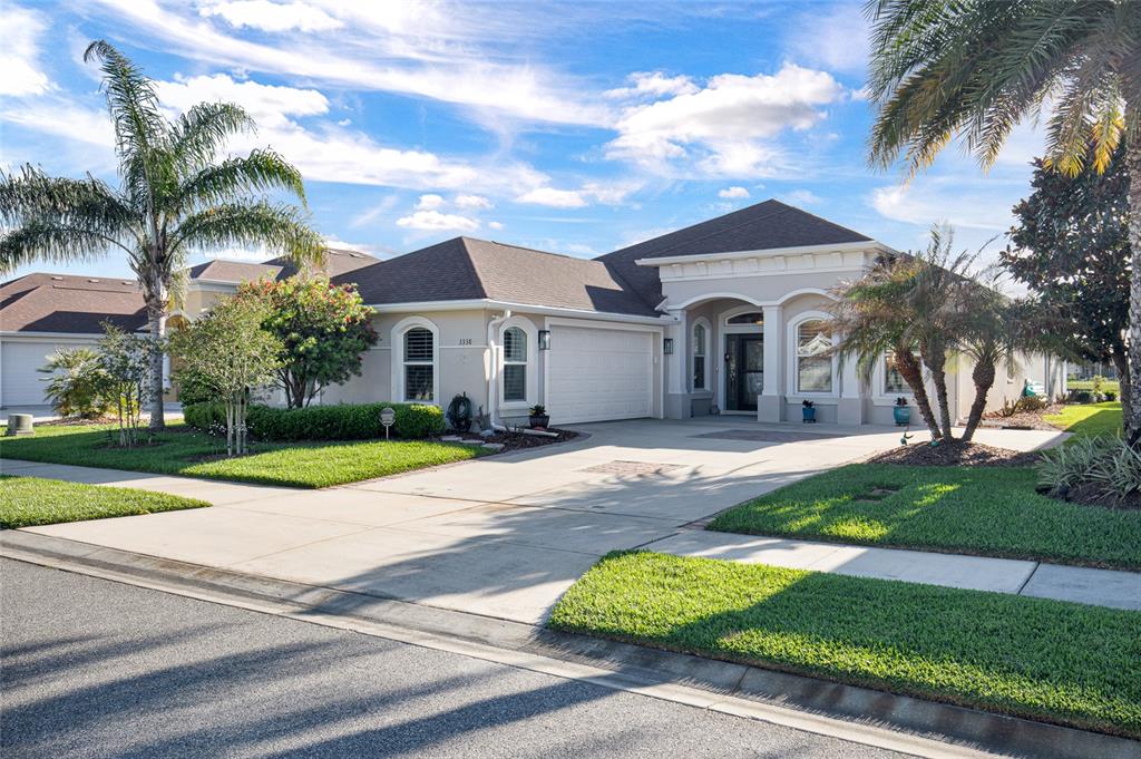 A single-story suburban house with a two-car garage, arched windows, and a palm-lined front yard — 3338 BELLINO BOULEVARD, NEW SMYRNA BEACH, FL