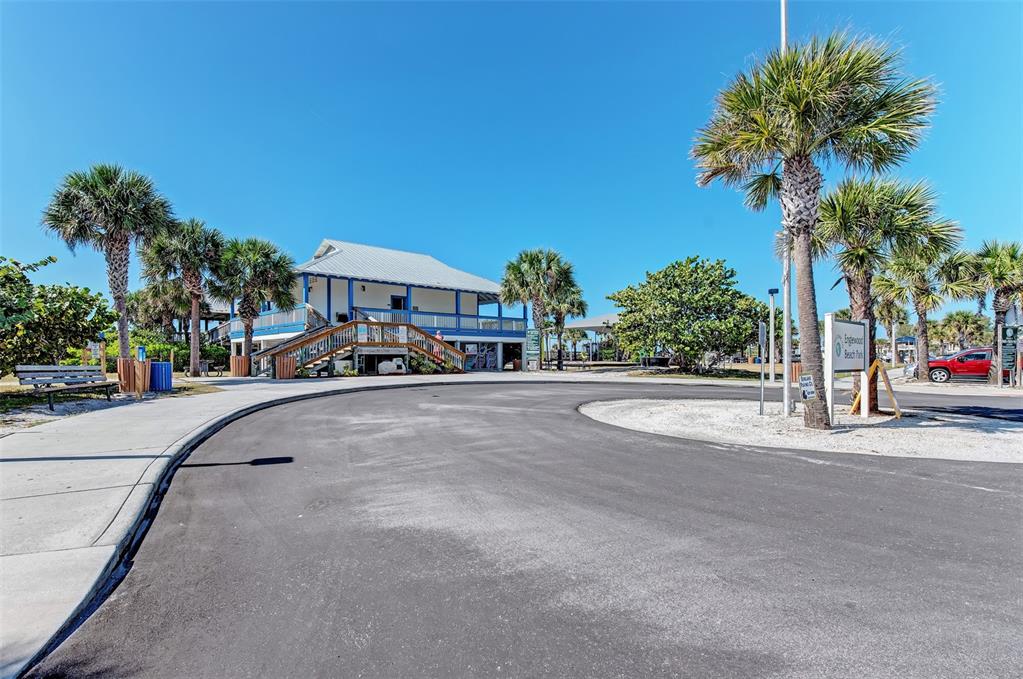 A two-story building with a wooden staircase stands near a paved parking lot and palm trees — 107 JENNIFER DRIVE, ROTONDA WEST, FL