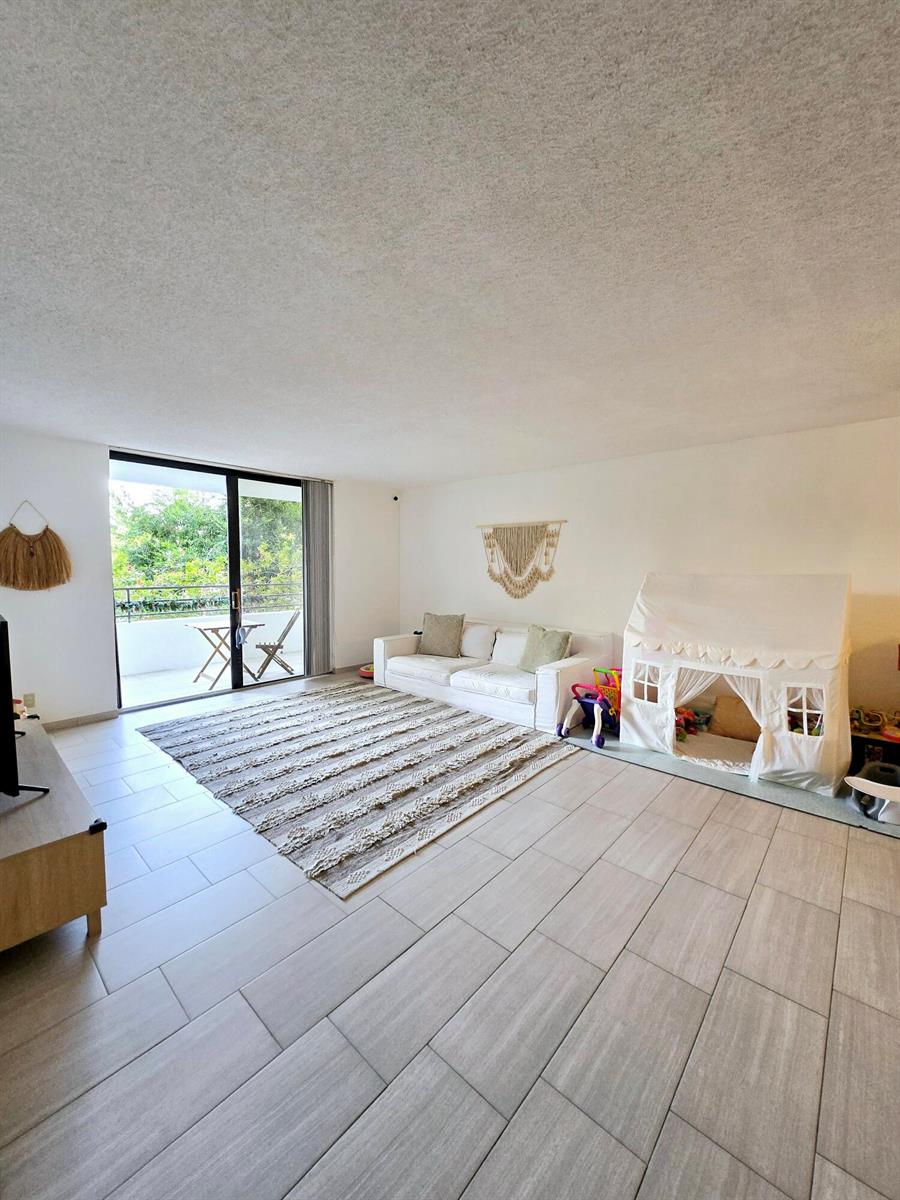 A living room features light tile floors, a white sofa, a play tent, and balcony access — 2500 Parkview Drive # 412, Hallandale Beach FL 33009, HALLANDALE BEACH, FL