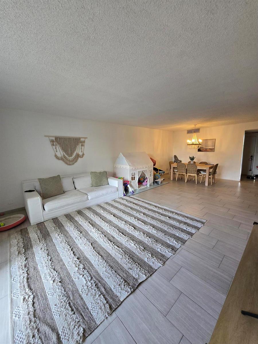 A living room with a white sofa, striped rug, play tent, and dining area — 2500 Parkview Drive # 412, Hallandale Beach FL 33009, HALLANDALE BEACH, FL