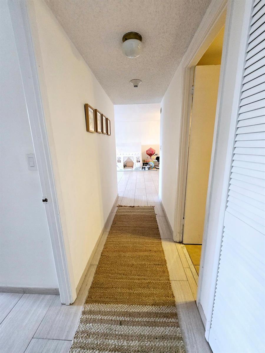 A hallway with white walls, tile flooring, a jute runner rug, and a ceiling light — 2500 Parkview Drive # 412, Hallandale Beach FL 33009, HALLANDALE BEACH, FL