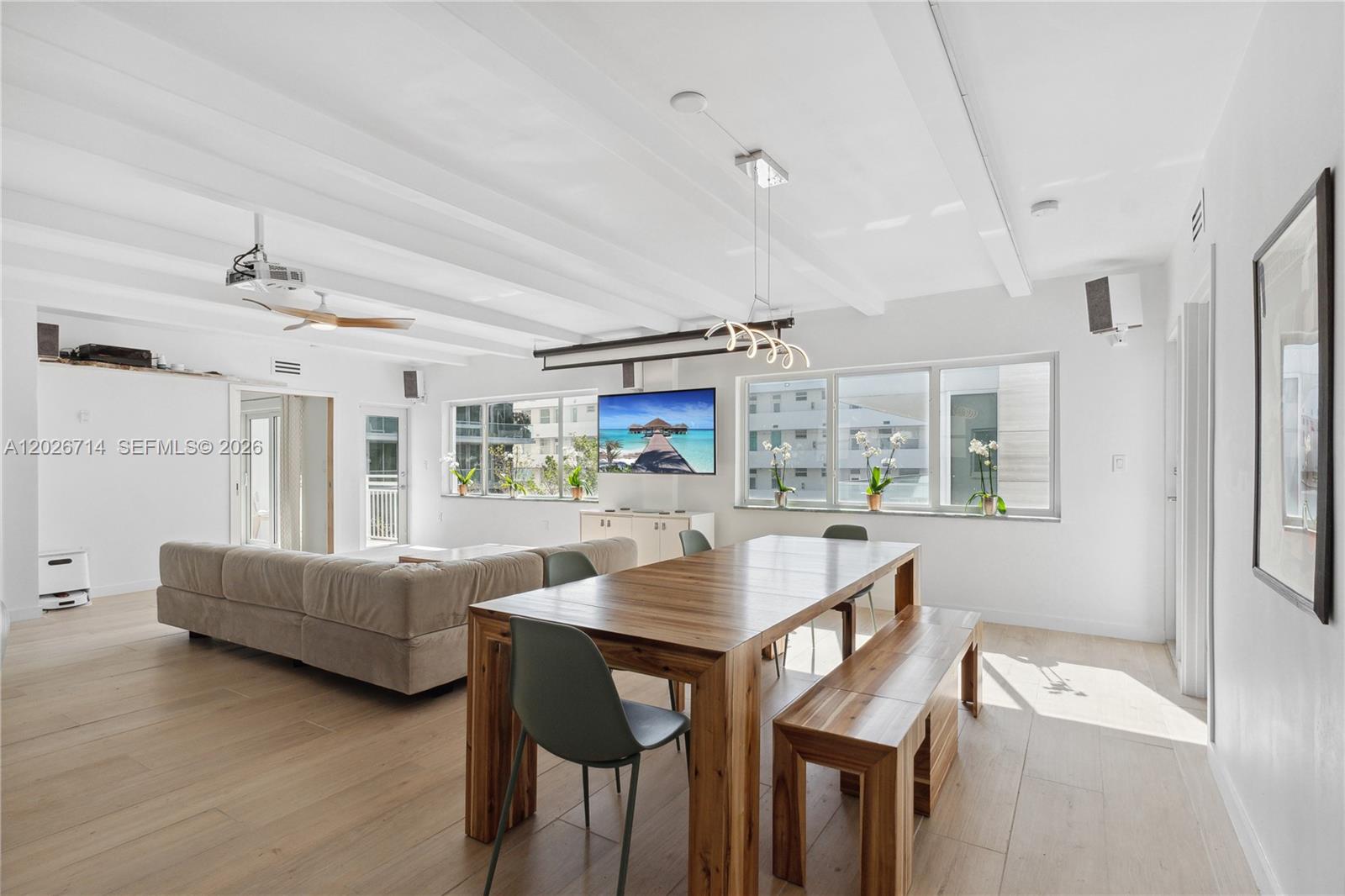 A bright, open-concept living and dining area features white beamed ceilings and wood flooring — 325 Ocean Dr # 502, Miami Beach FL 33139, MIAMI BEACH, FL