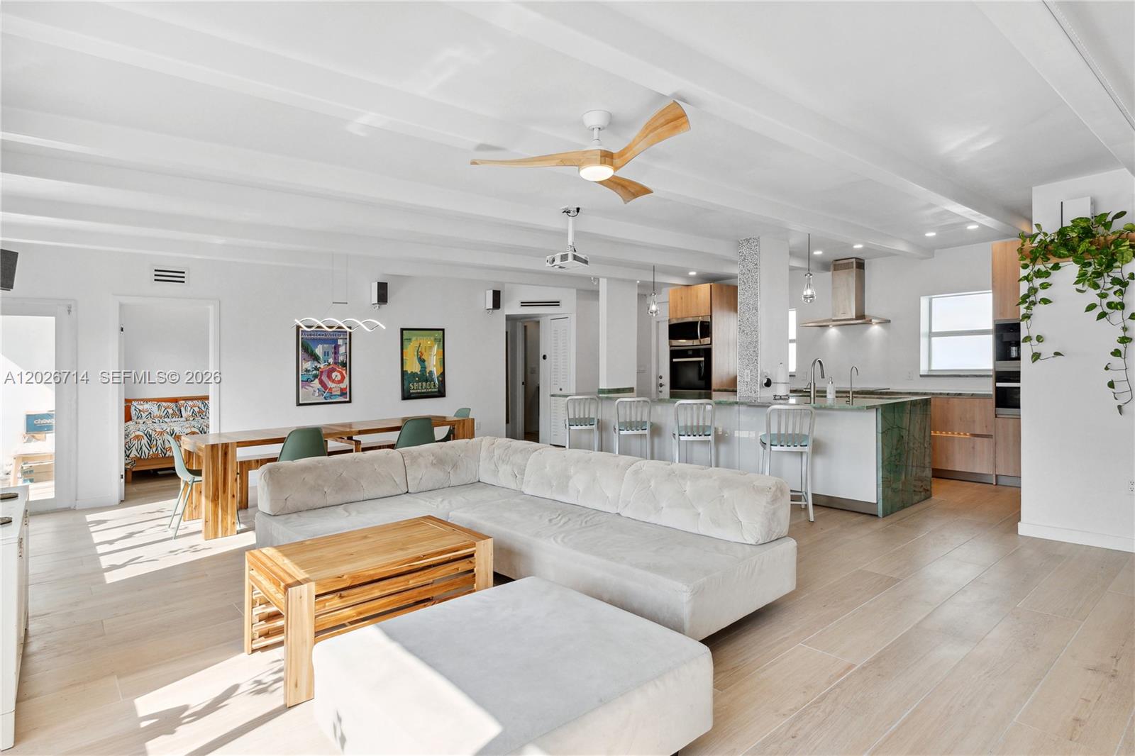 An open-concept living room and kitchen feature light wood flooring, a sectional sofa, and island seating — 325 Ocean Dr # 502, Miami Beach FL 33139, MIAMI BEACH, FL