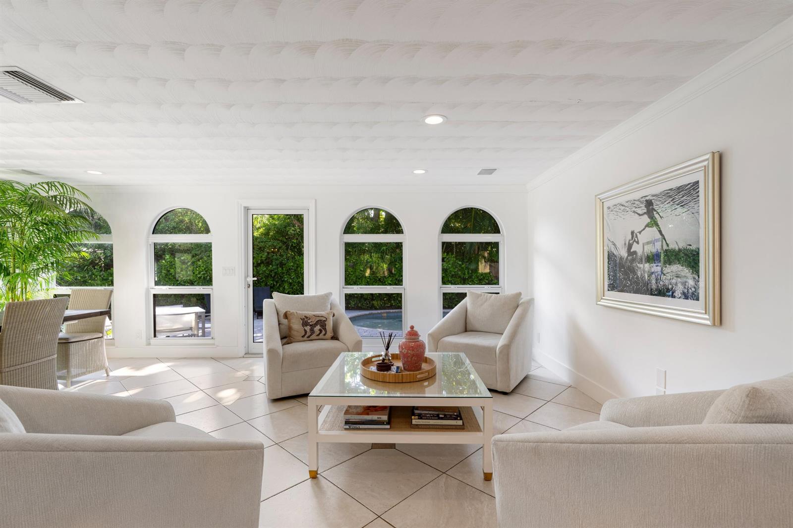 A bright living room features four armchairs, a glass coffee table, and arched windows — 35 Anna Street, Ocean Ridge FL 33435, OCEAN RIDGE, FL