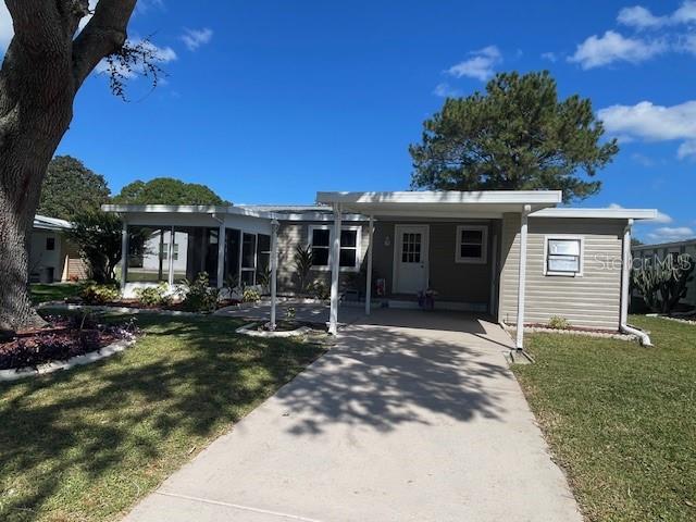 A single-story house with a carport, a screened-in porch, and light-colored siding — 909 ORCHID STREET, LADY LAKE, FL