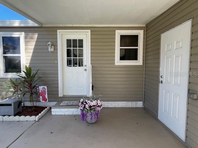 A covered porch features two white doors, a window, and a potted plant — 909 ORCHID STREET, LADY LAKE, FL