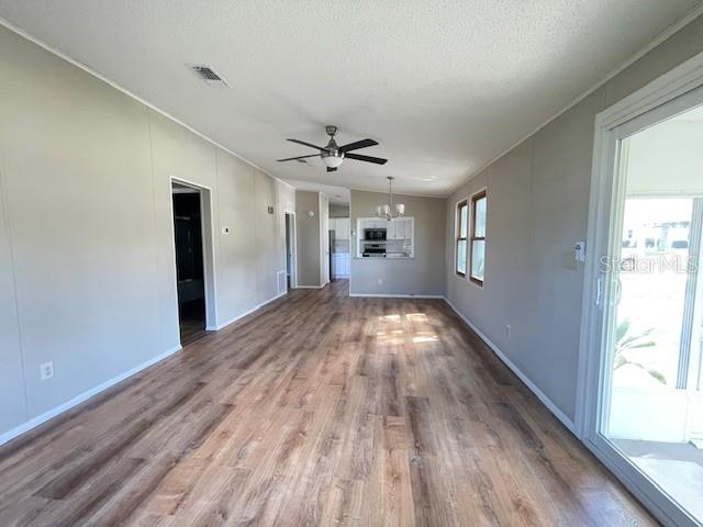 A living area features wood-look flooring, a ceiling fan, and a view into the kitchen — 909 ORCHID STREET, LADY LAKE, FL