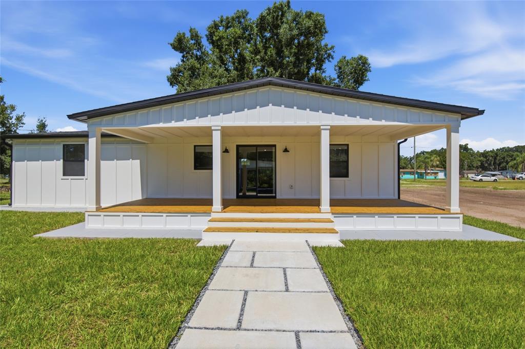 A white house with a large front porch, board-and-batten siding, and a stone walkway — 3845 RAMBLER AVENUE, ST CLOUD, FL