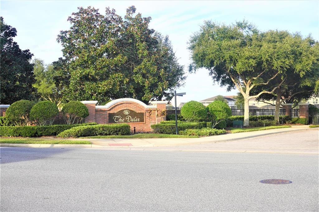 A brick entrance sign for The Dales neighborhood stands behind a manicured hedge and trees — 1315 YORKSHIRE COURT, DAVENPORT, FL