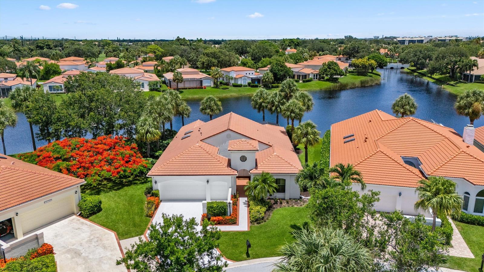 An aerial view shows suburban houses with orange tile roofs near a lake and trees — 3526 Lantern Bay Drive, Jupiter FL 33477, JUPITER, FL