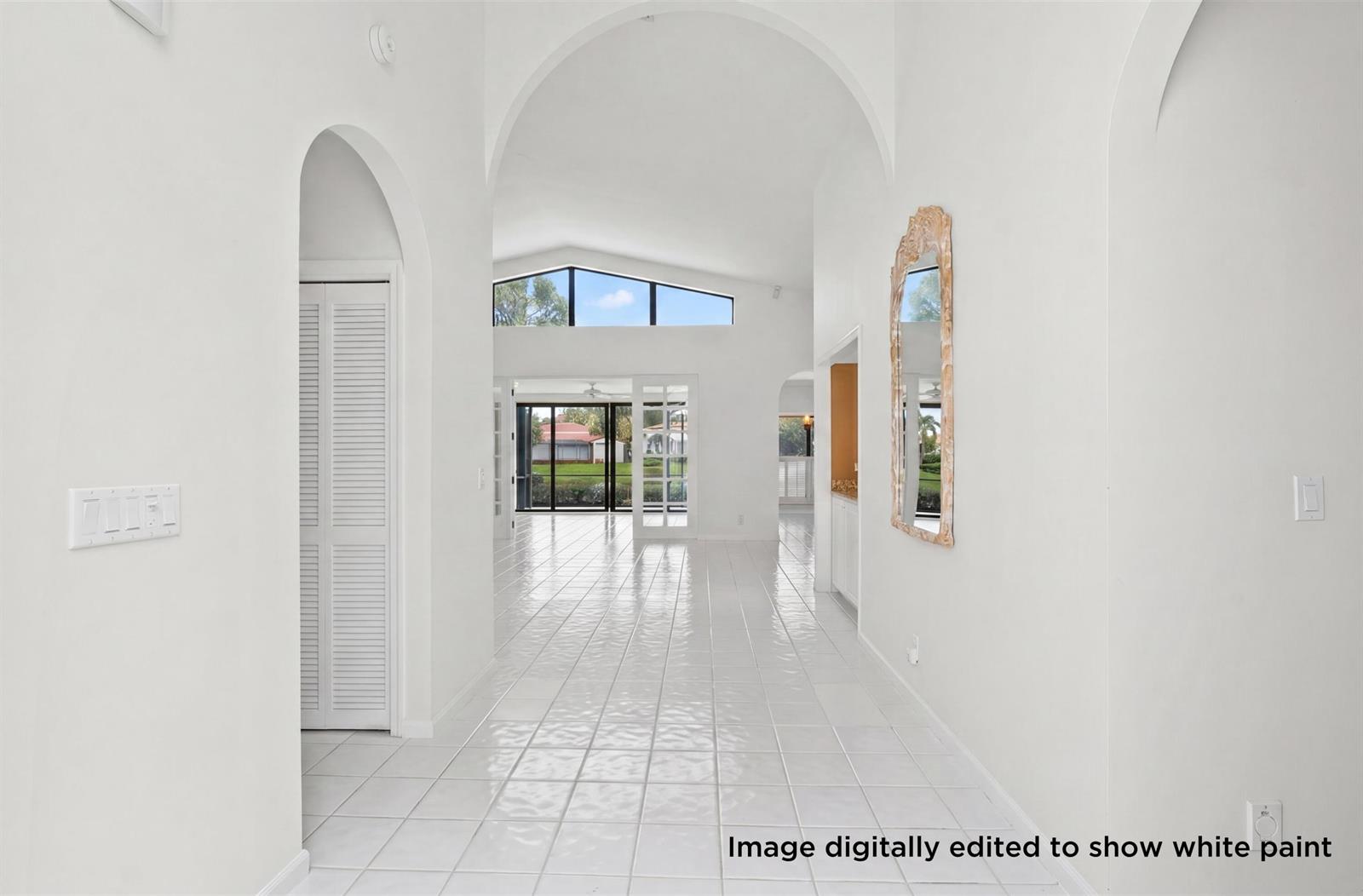 A bright hallway with white tile floors leads toward a living area with large windows — 3526 Lantern Bay Drive, Jupiter FL 33477, JUPITER, FL