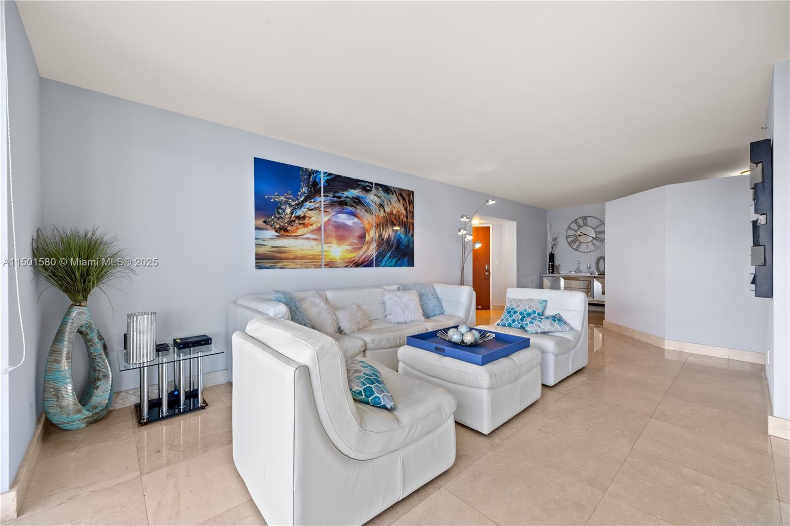 A living room features white leather seating, a wave-themed triptych painting, and light tile flooring — 6365 Collins Ave # 4106, Miami Beach FL 33141, MIAMI BEACH, FL