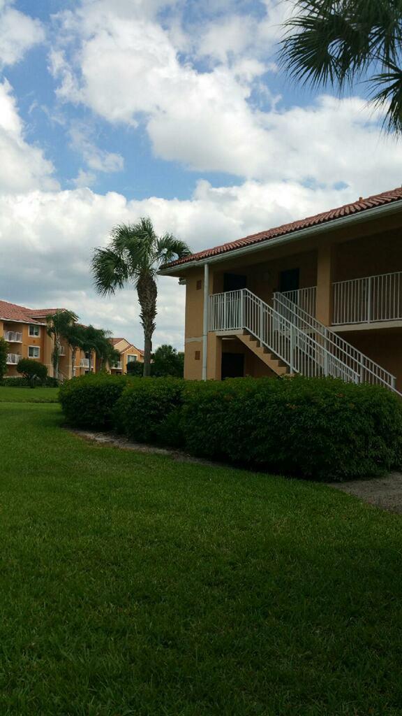A multi-story apartment building with a white staircase and palm trees on a grassy lawn — 141 SW Palm Drive # 202, FL 34986, FL