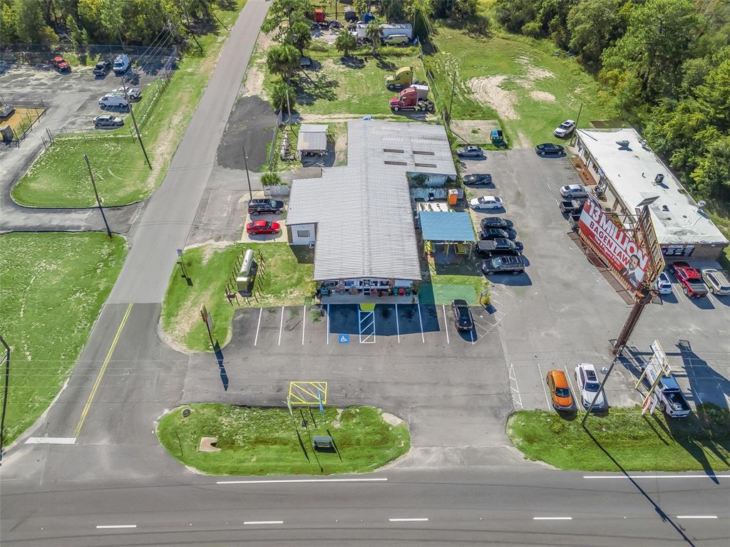 An aerial view shows a commercial building with a parking lot and a large billboard — 9594 SE MARICAMP ROAD, OCALA, FL