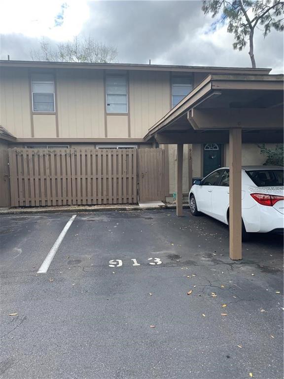 A two-story townhouse exterior features a private fenced patio and a covered parking space — 913 BUCK COURT, BRANDON, FL
