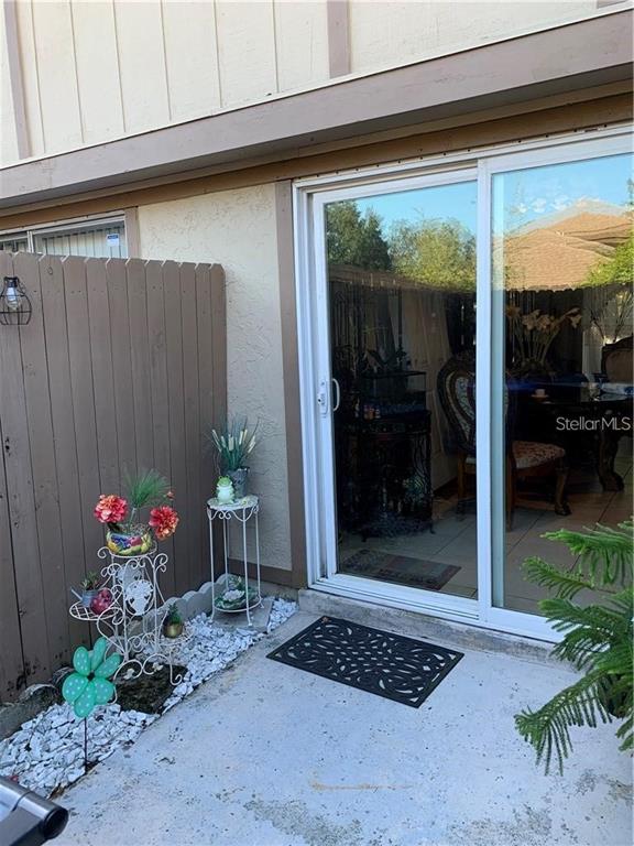 A patio features a sliding glass door, a wooden privacy fence, and potted plants — 913 BUCK COURT, BRANDON, FL
