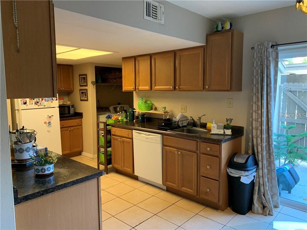 A kitchen with wood cabinets, dark countertops, a white dishwasher, and tile flooring — 913 BUCK COURT, BRANDON, FL