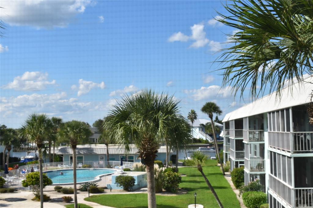 An exterior view of a multi-story apartment building overlooking a swimming pool and palm trees — 325 N CAUSEWAY UNIT C 304, NEW SMYRNA BEACH, FL