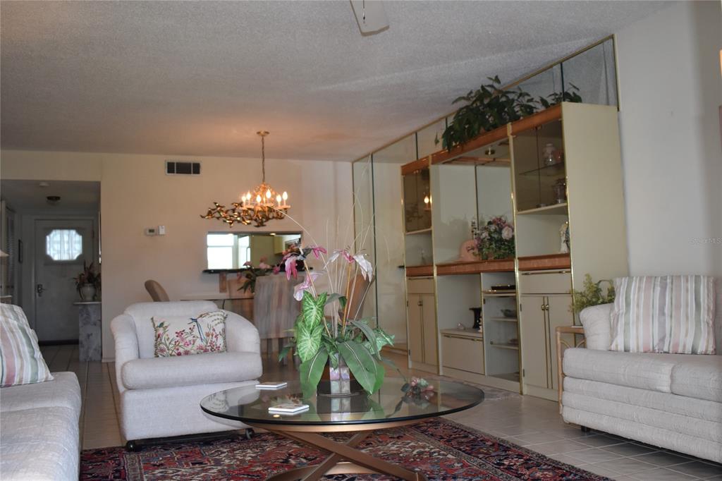 A living room features a glass coffee table, white armchairs, and a large built-in wall unit — 325 N CAUSEWAY UNIT C 304, NEW SMYRNA BEACH, FL