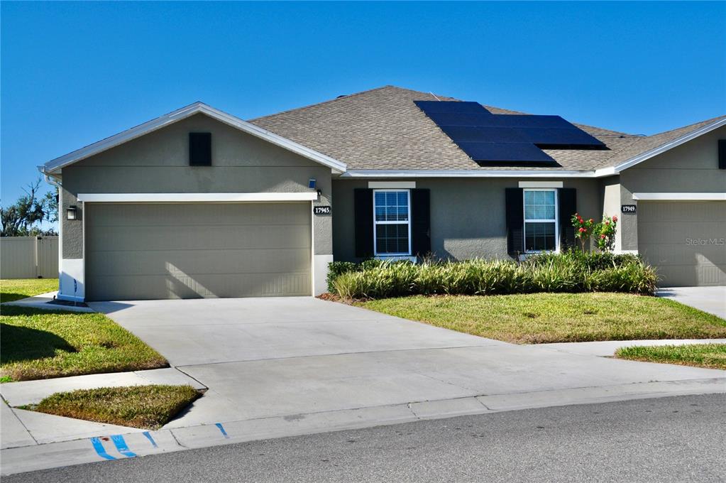 A single-story house with a two-car garage, solar panels on the roof, and a driveway — 17945 TURNING LEAF CIRCLE, LAND O LAKES, FL