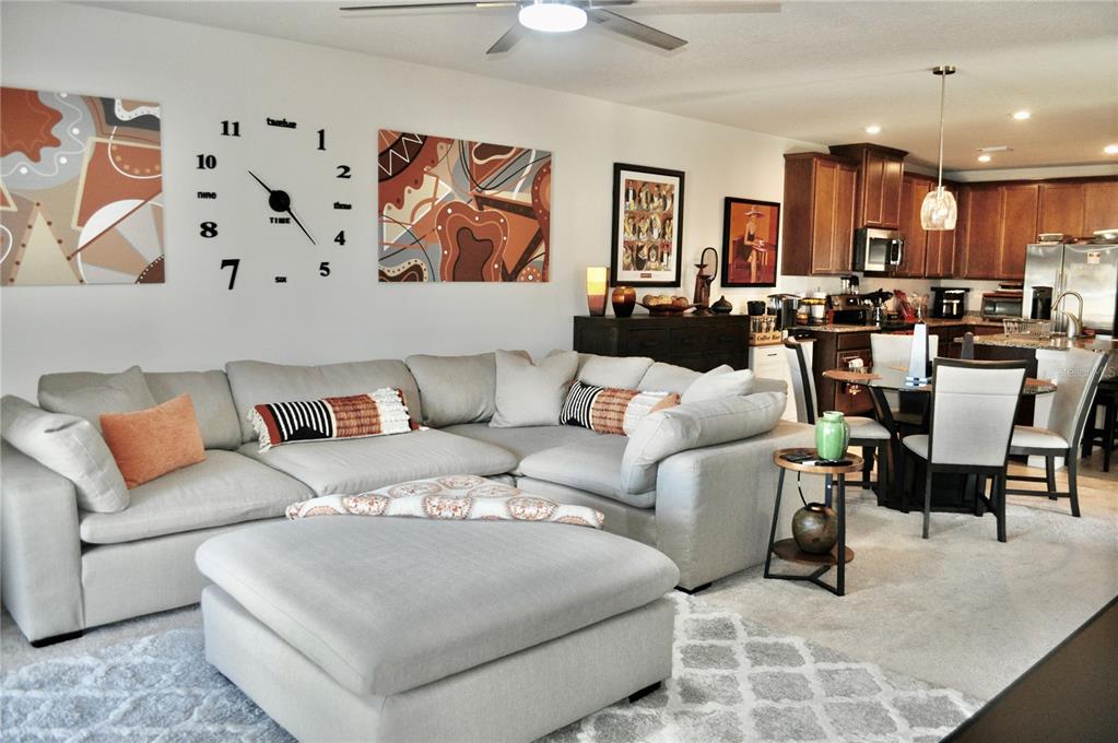 A living room with a large sectional sofa, ottoman, and an open-concept kitchen — 17945 TURNING LEAF CIRCLE, LAND O LAKES, FL