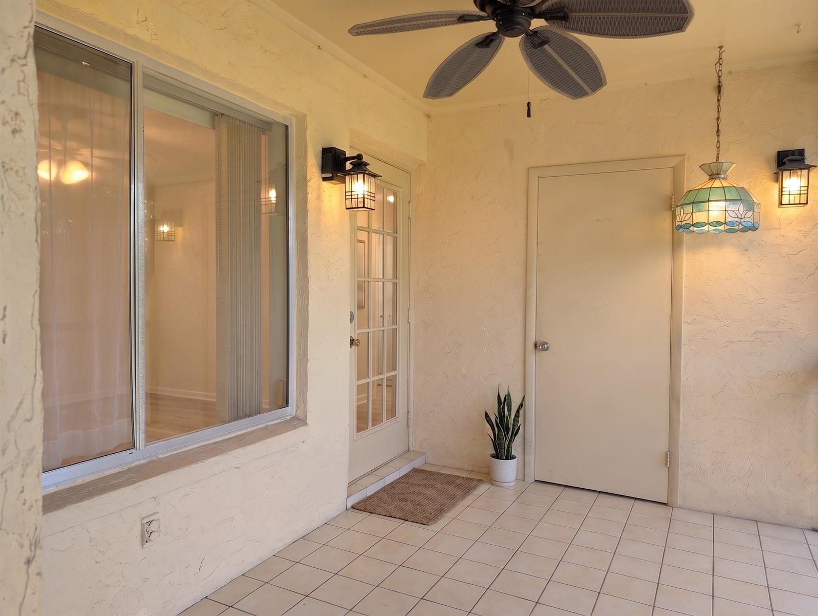 A covered patio features tiled flooring, a ceiling fan, two wall sconces, and a hanging lamp — 327 Pine Ridge Circle # 2, FL 33463, FL