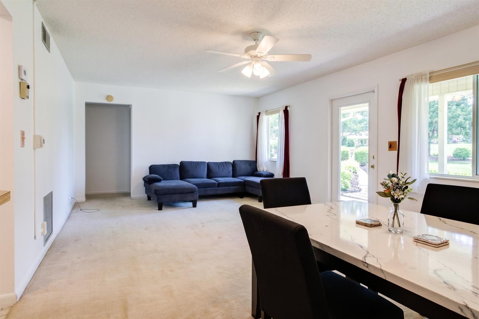 A living and dining area features a blue sectional sofa, white walls, and carpeted floors — 327 Pine Ridge Circle # 2, FL 33463, FL