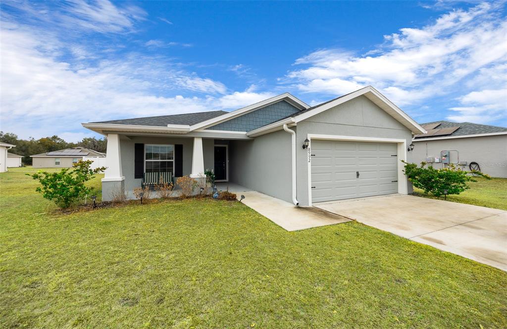 A single-story house with a gray stucco exterior, a two-car garage, and a covered porch — 8992 SE 42ND COURT, OCALA, FL