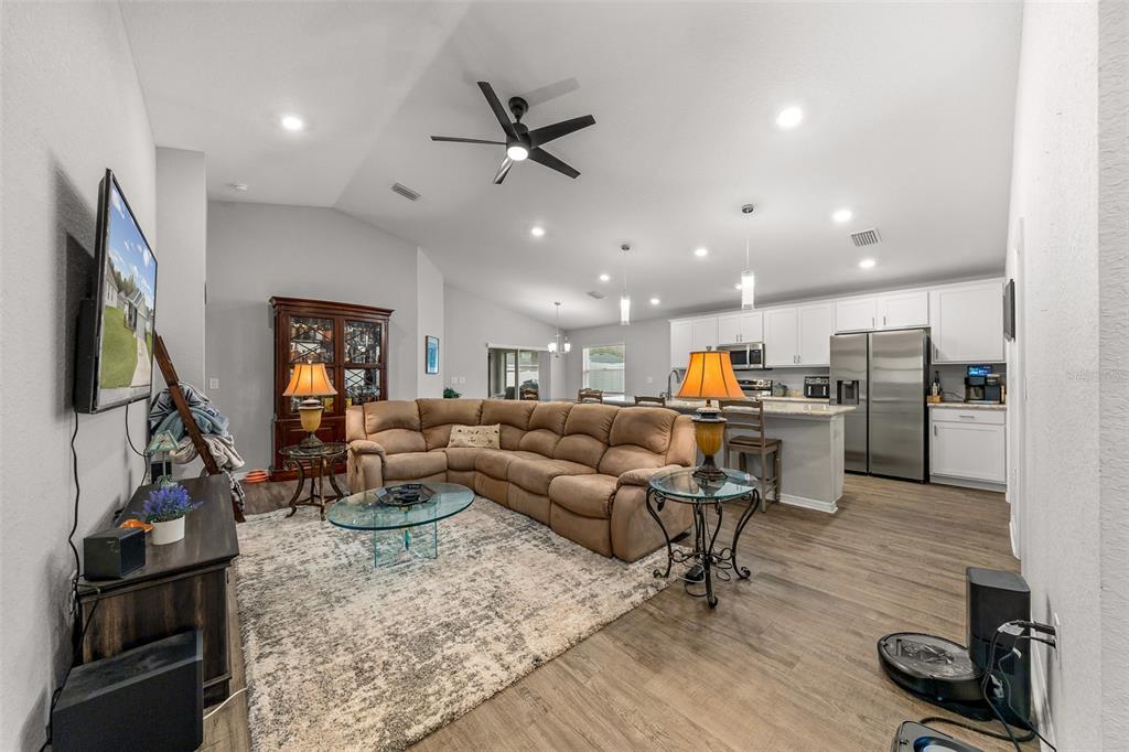 A living room with a sectional sofa, area rug, and an open-concept kitchen with appliances — 8992 SE 42ND COURT, OCALA, FL