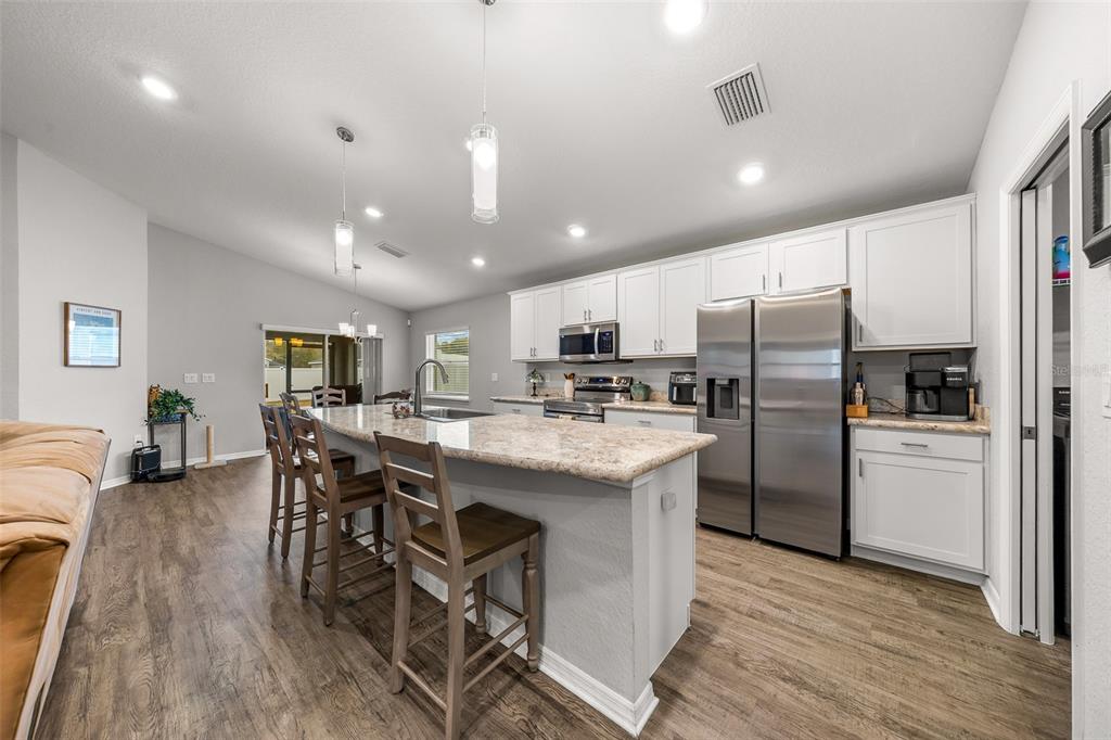 A kitchen with white cabinets, stainless steel appliances, and a granite-topped island with bar stools — 8992 SE 42ND COURT, OCALA, FL